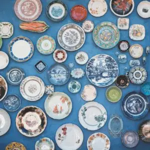 Home 22 Composition of various decorative ornamental plates of different sizes and colors arranged on blue wall